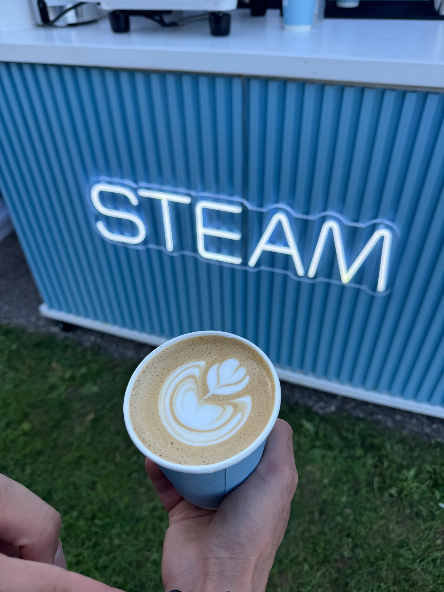 Latte art in front of the blue STEAM coffee cart